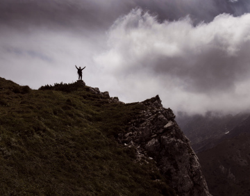 A Figure Of A Man On A Mountain Peak